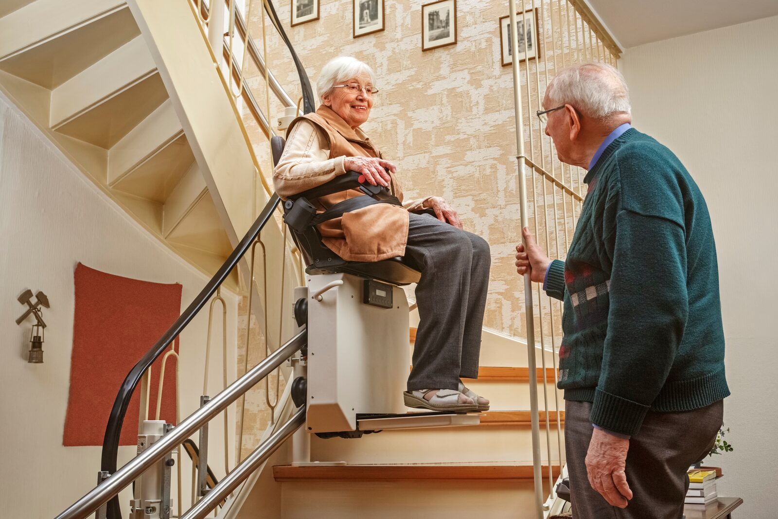Older couple — wife on a curved stairlift, husband watching